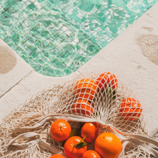 a photo of a net bag of oranges on the side of a pool