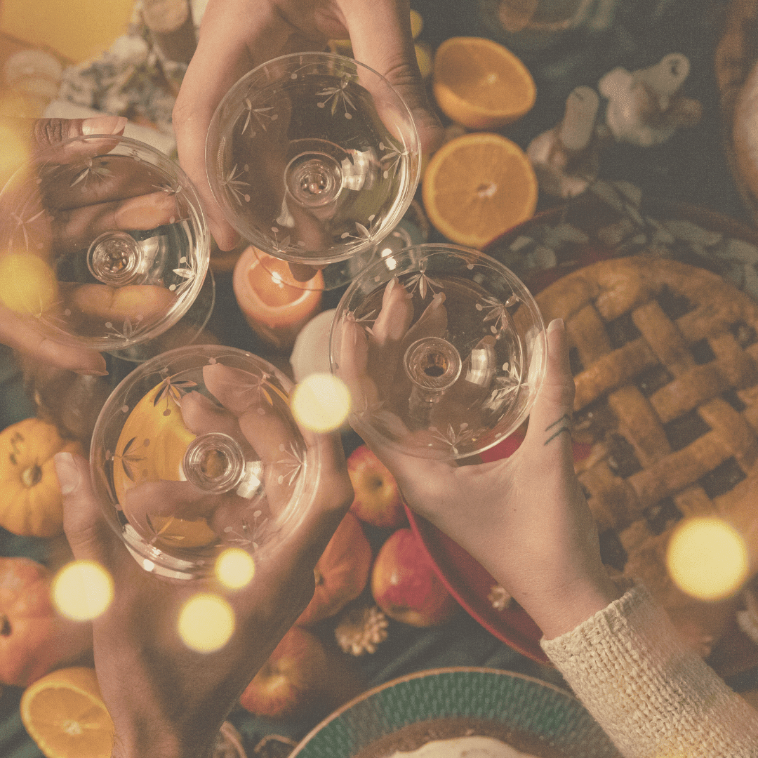 four glasses meeting to cheers over a thanksgiving table