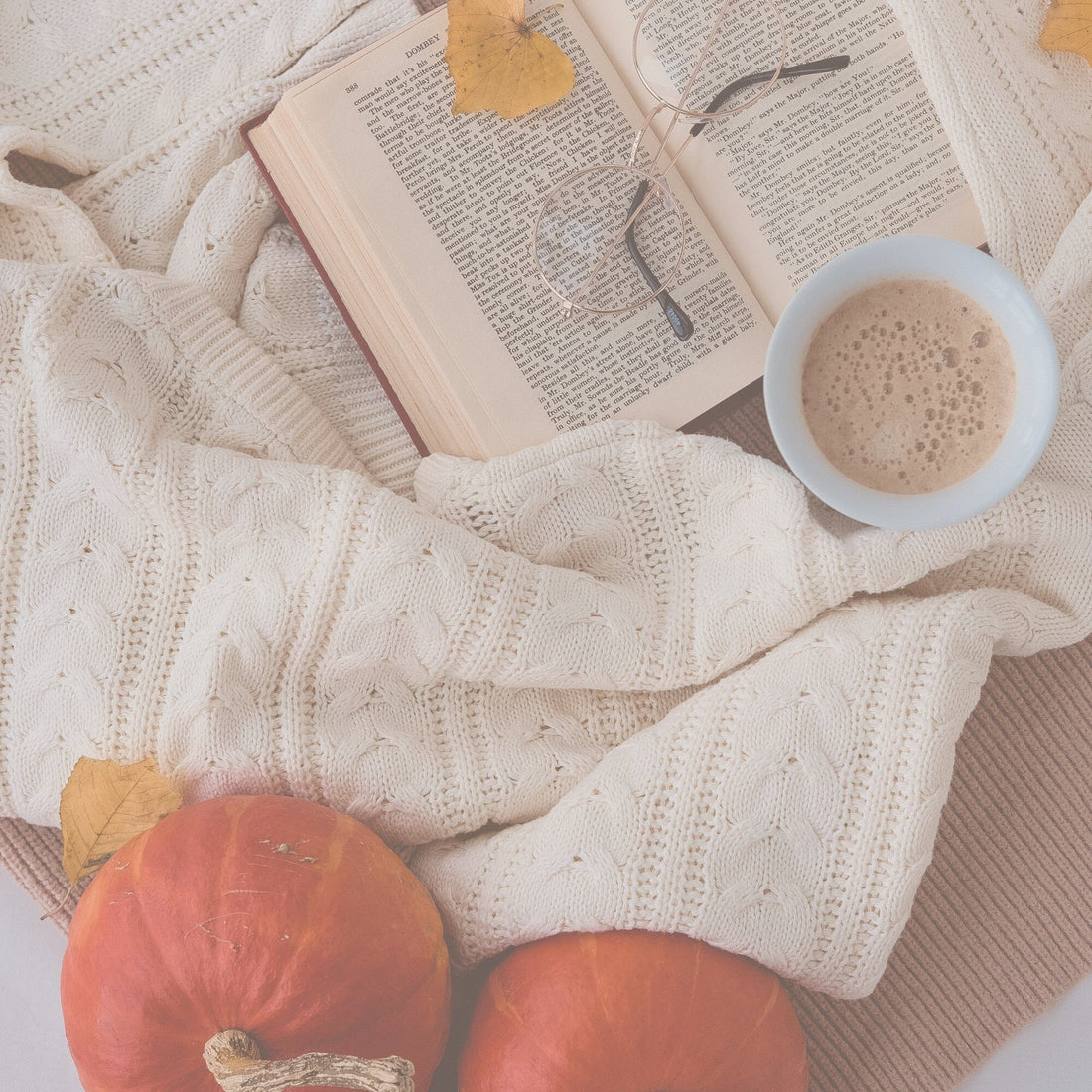 photo of a knit blanket with an open book, pumpkins and a cup of coffee